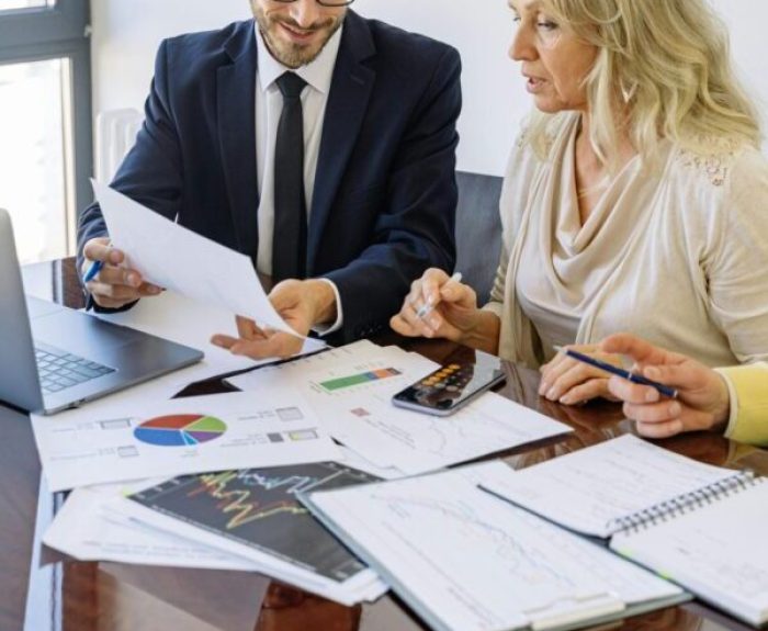 Two business professionals reviewing financial documents and graphs during a meeting.